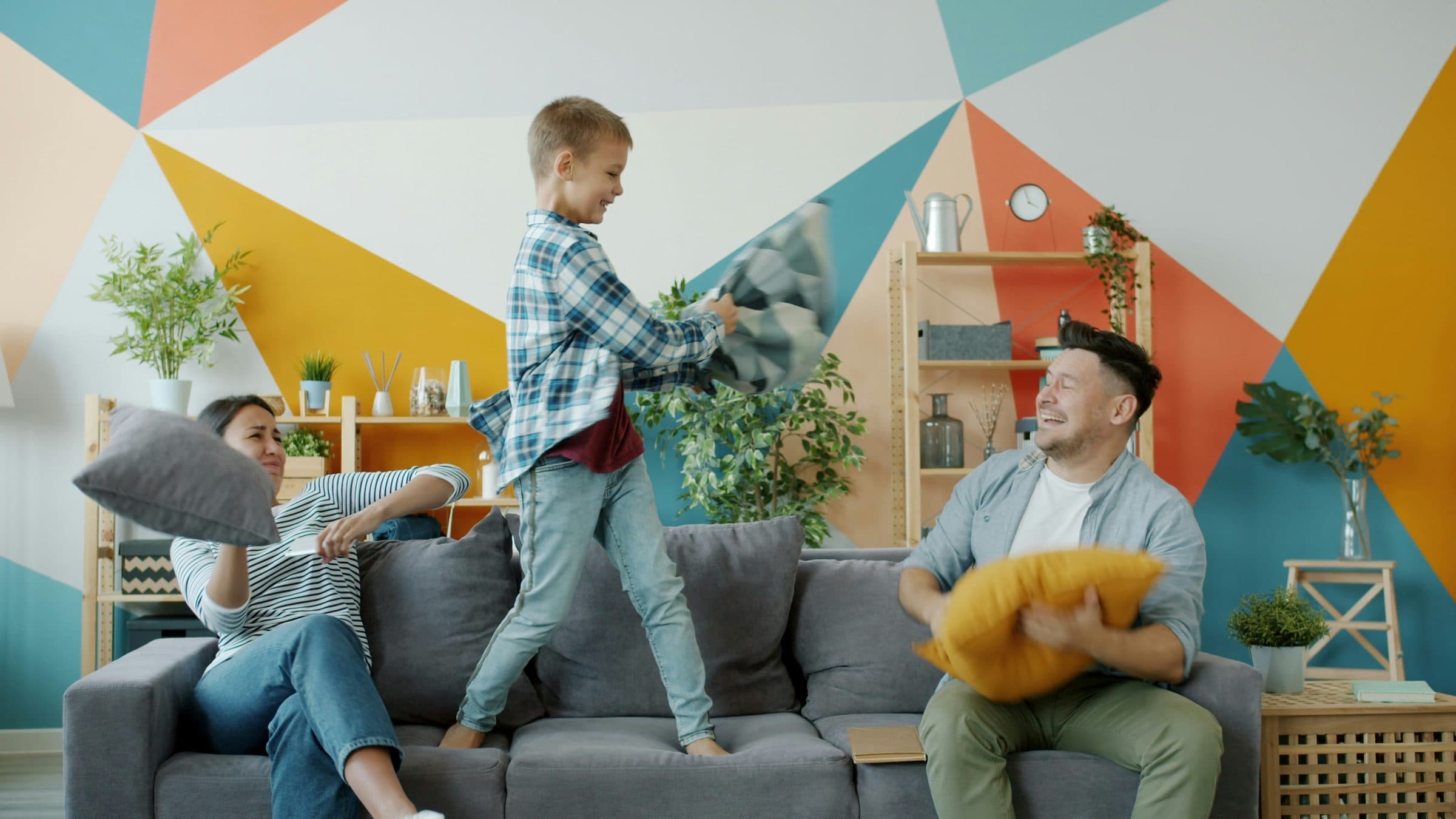A family having a pillow fight on the couch at home