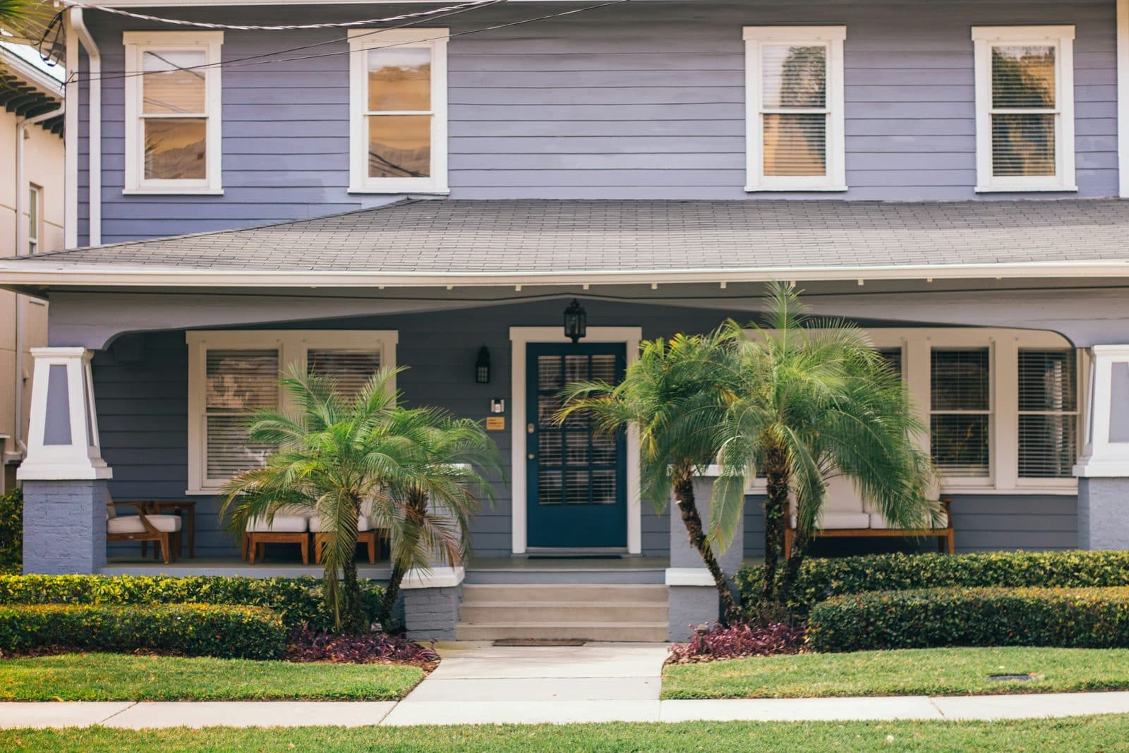 A two-story house with a wide front porch and palm trees