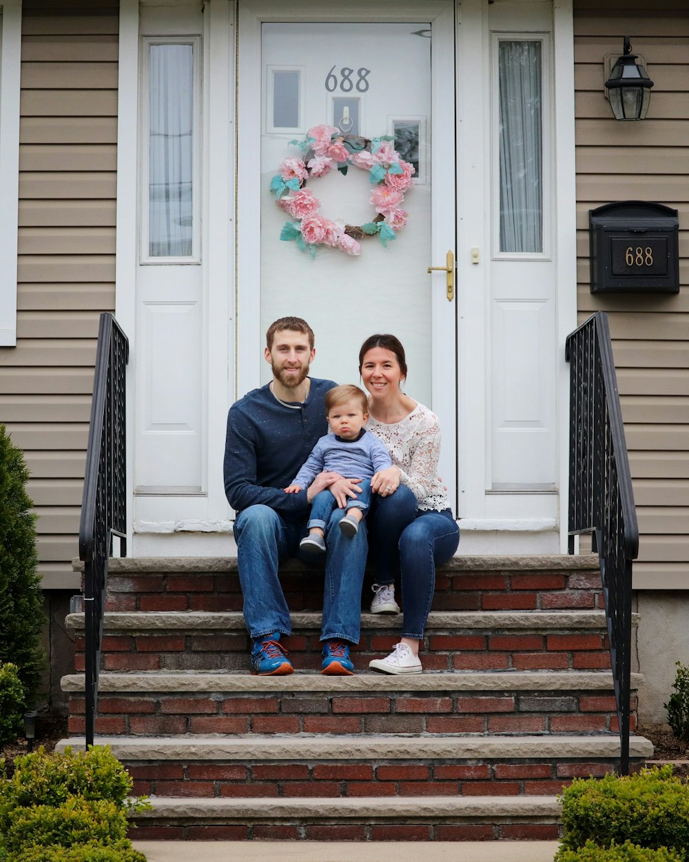 A family smiling on the front steps of their home