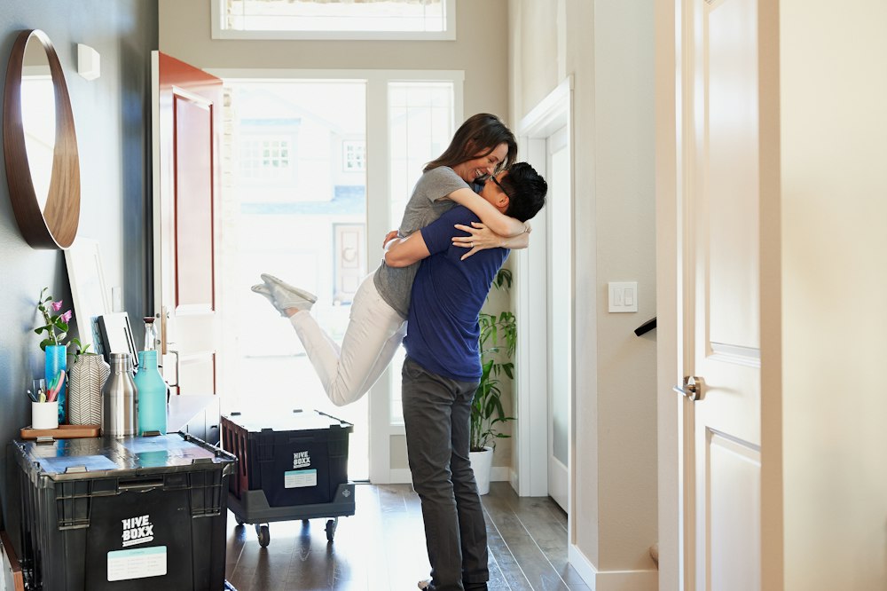 A couple hugging in their new home among moving boxes