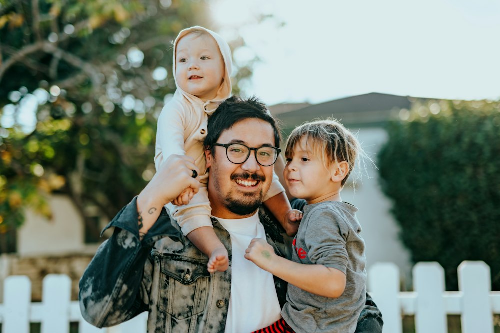 A dad carrying his two kids outside their home