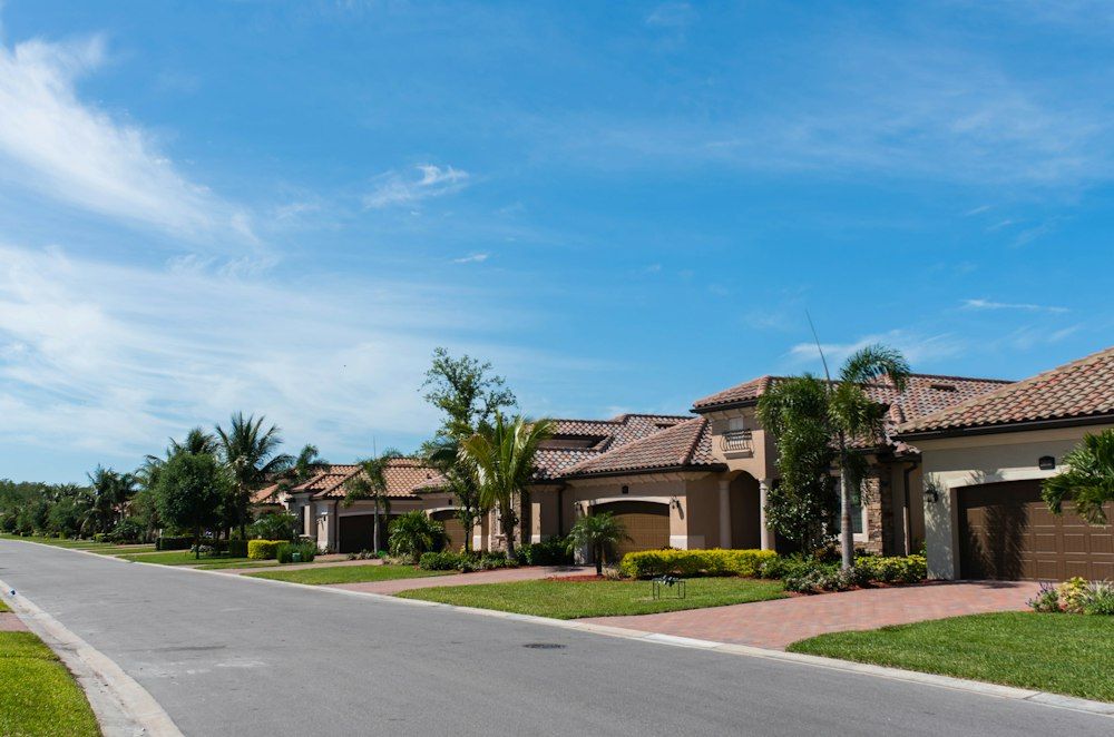 A sunny street of homes with palm trees and tile roofs